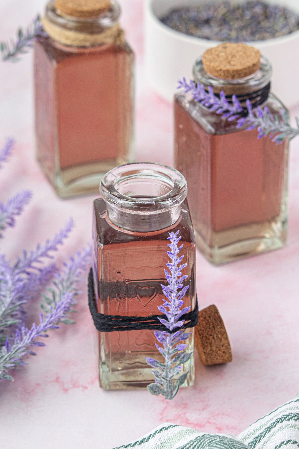 A glass jar of lavender simple syrup next to some fresh lavender.