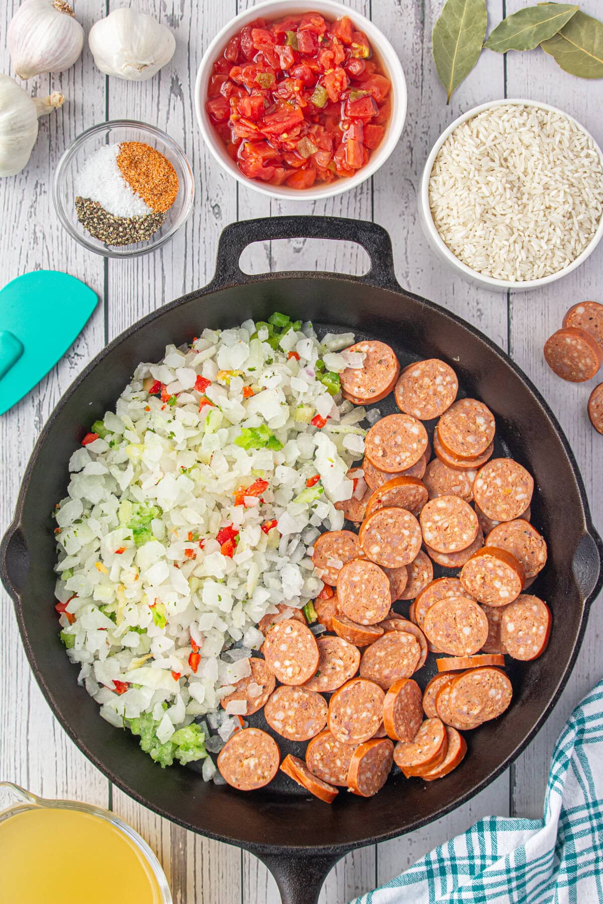 Onions, peppers, and sliced sausage in a skillet.