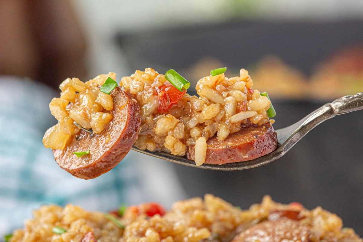 A close-up view of smoked sausage jambalaya on a fork.