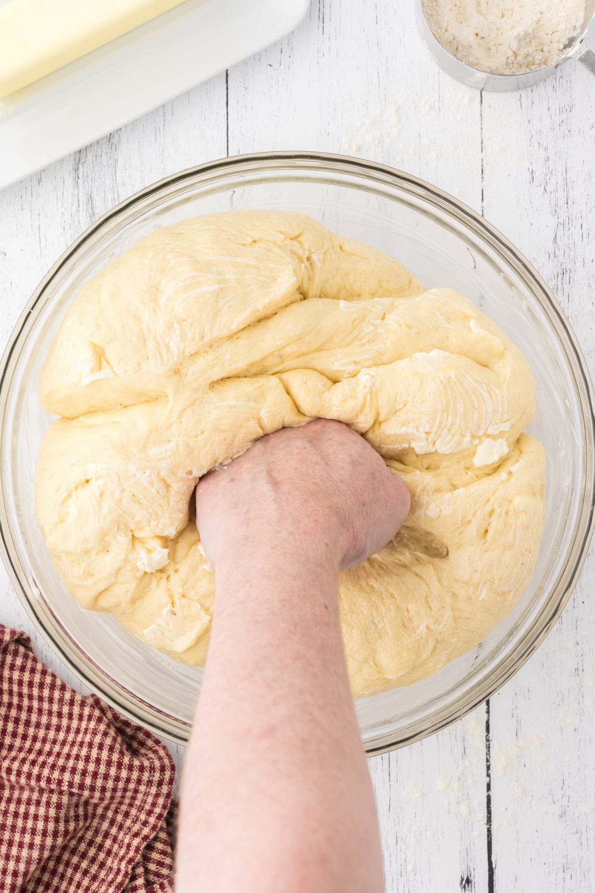 A hand punching down risen dough.