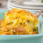 Closeup of a serving of cheesy Southern squash casserole being lifted from the dish.
