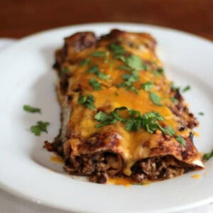 Closeup of beef enchiladas on a white plate.