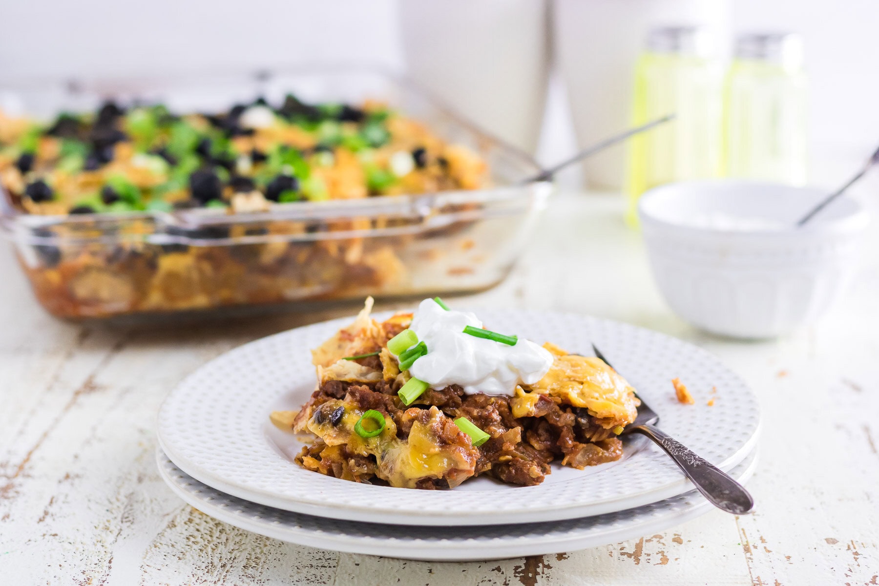 A serving of beef nacho casserole topped with sour cream on a serving plate.