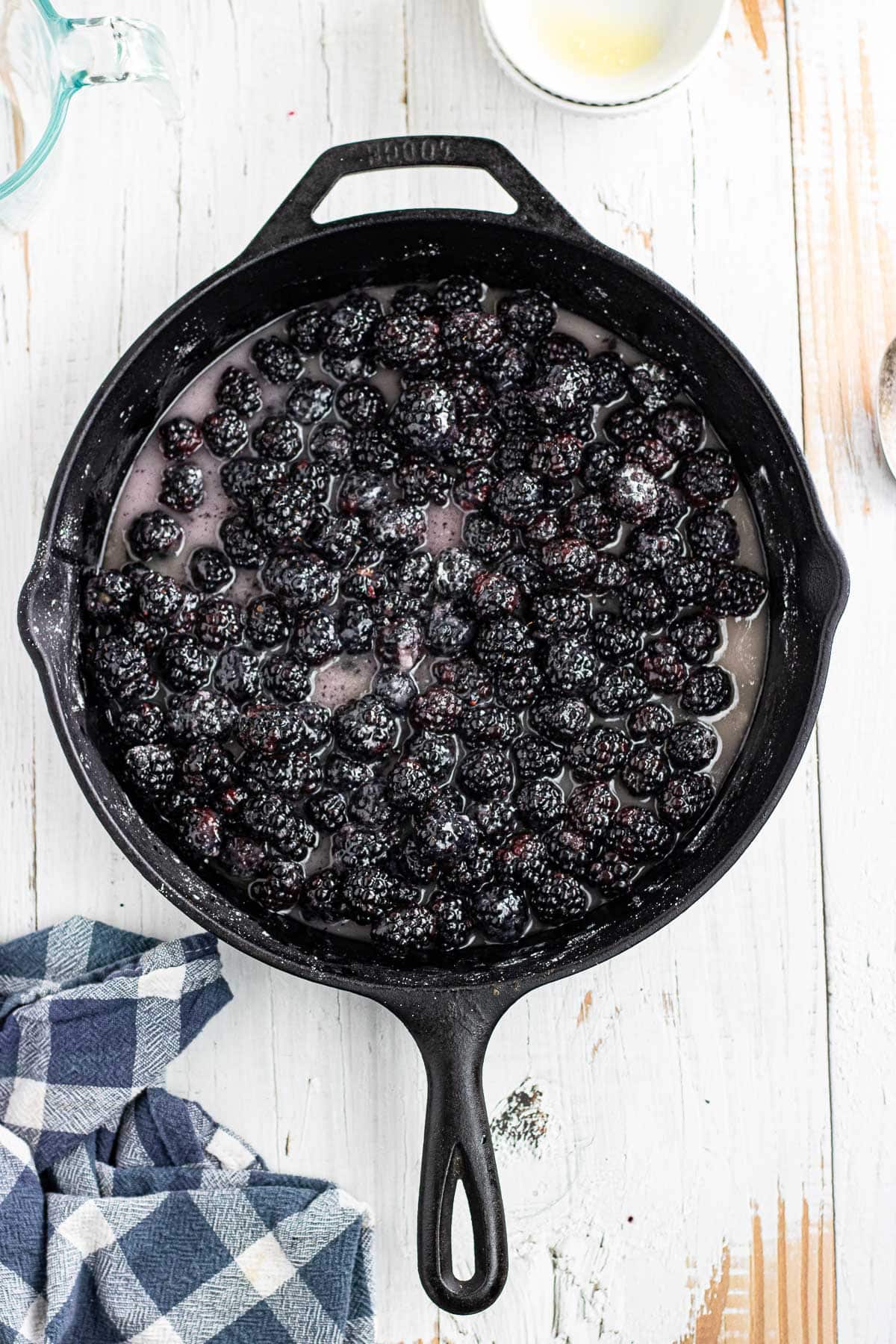 Simmering the blackberries and sugar in the skillet with butter, water, and vanilla.