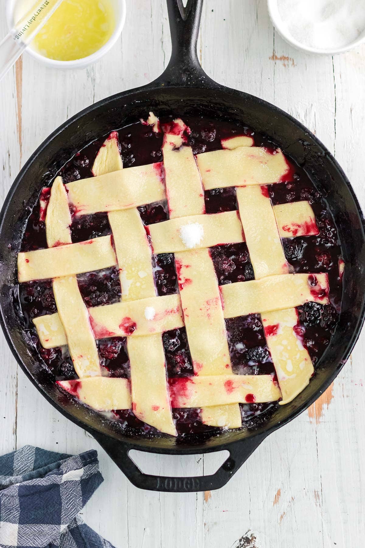 The unbaked pie crust strips arranged in a lattice pattern over the blackberry cobbler.