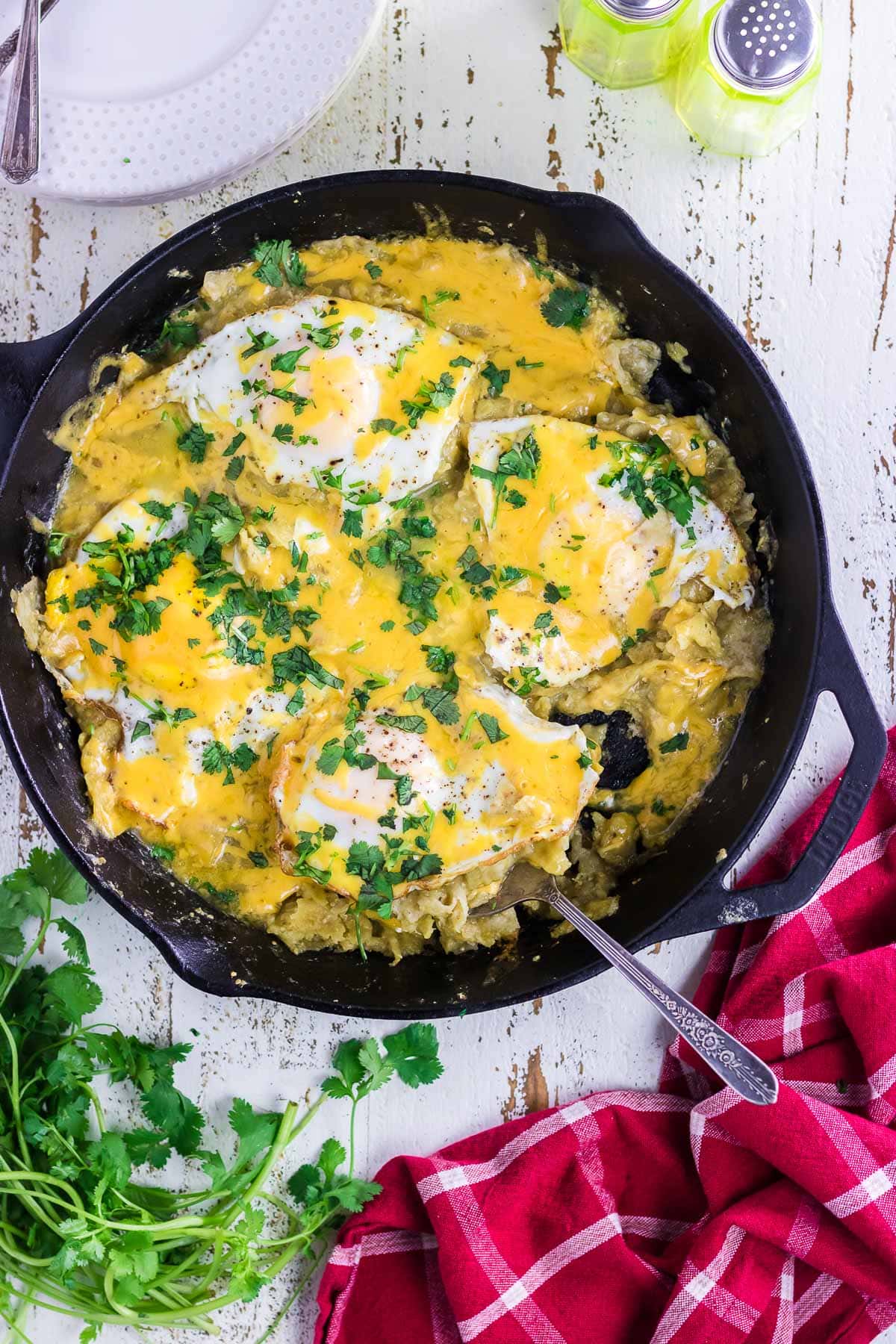 Green chilaquiles in a skillet with a serving spoon.