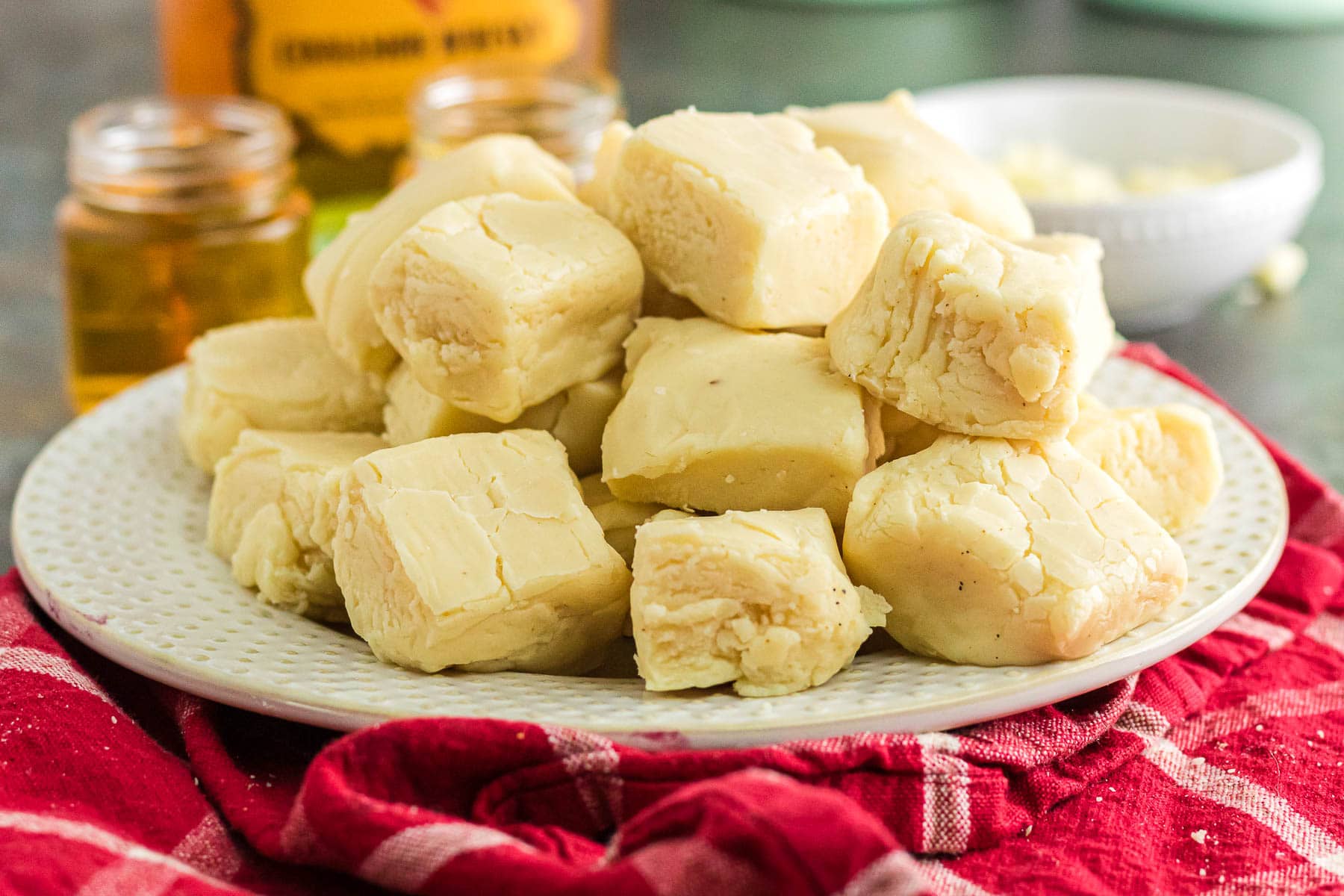 White chocolate fireball fudge on a plate with fireball whiskey in the background.