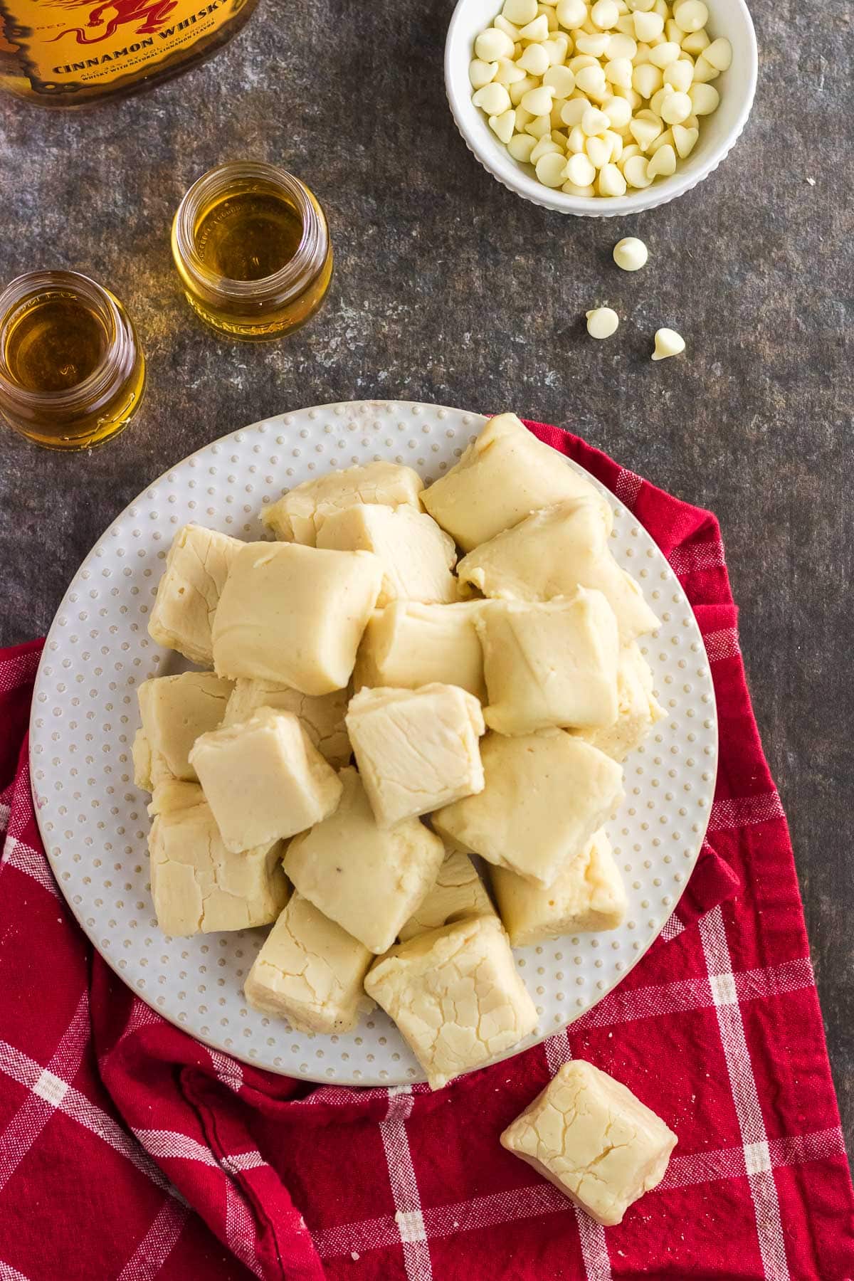 A plate of fireball fudge next to white chocolate chips and fireball whiskey.