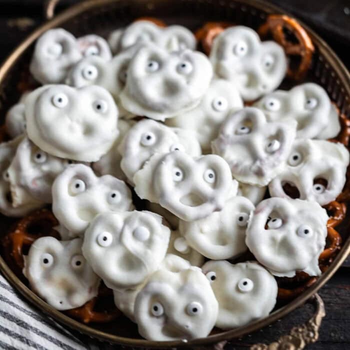 Small pretzels covered in white chocolate with candy eyes in a bowl.