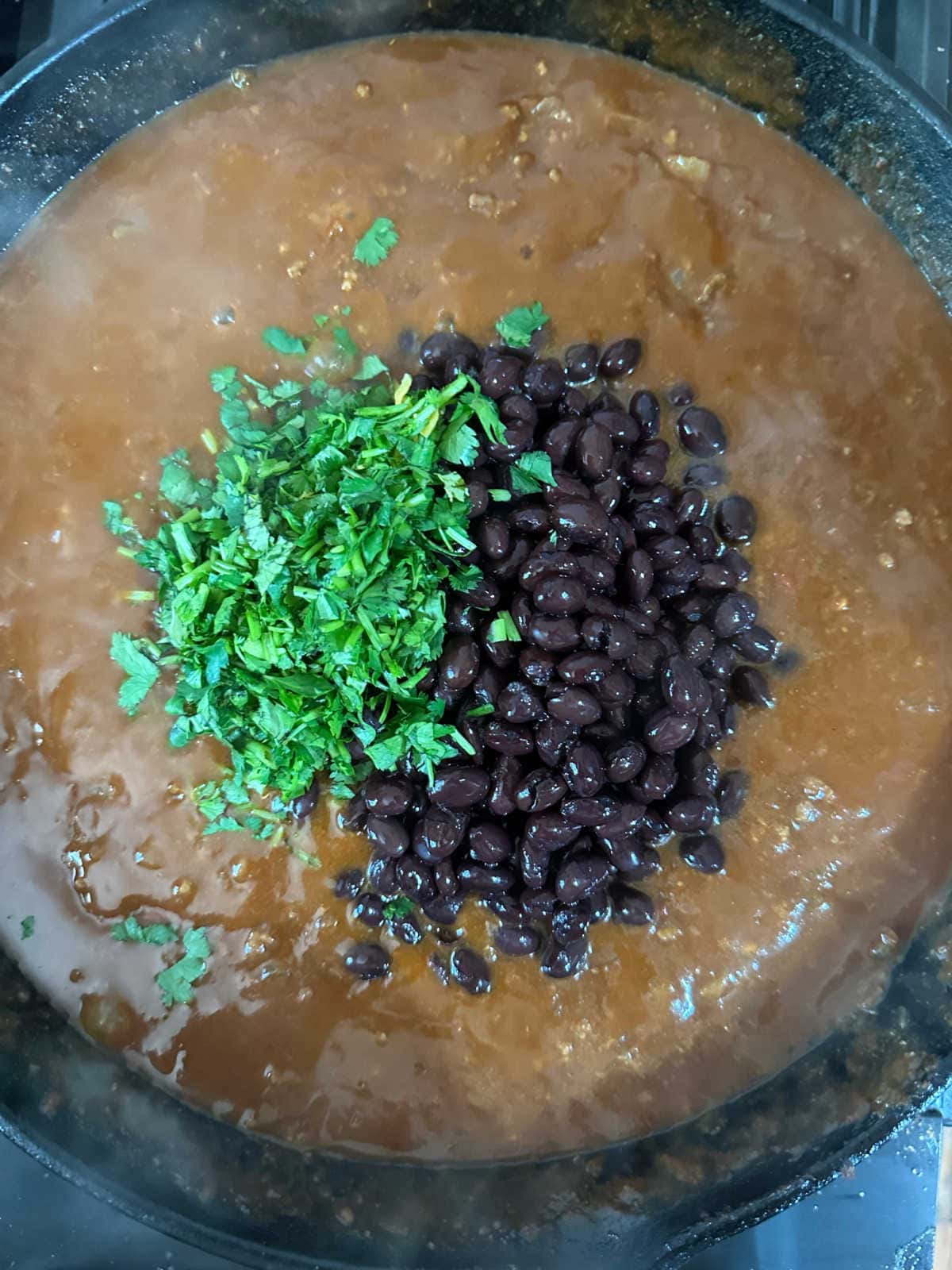 Black beans and cilantro stirred into the meat and sauce.