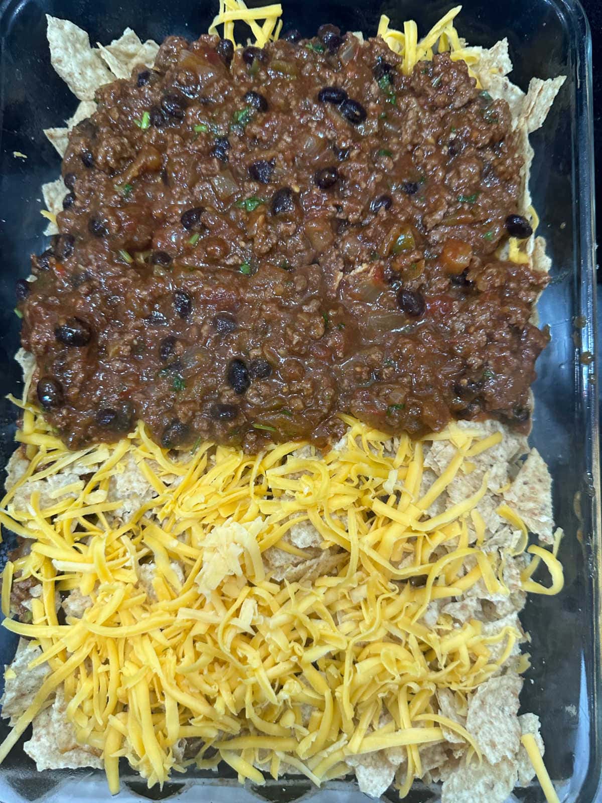 Another layer of chips, cheese, and beef added to the casserole.