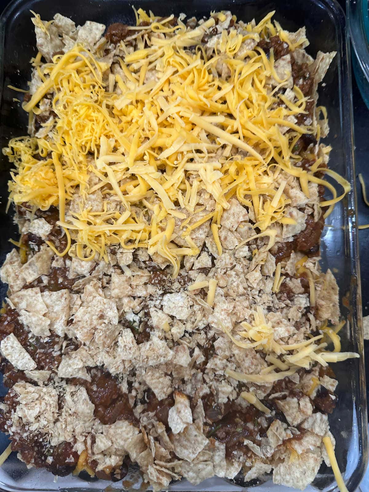 The final layer of beef, chips, and cheese in the casserole dish.