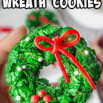 Fingers holding up a finished corn flake wreath cookie with a title text overlay for Pinterest.