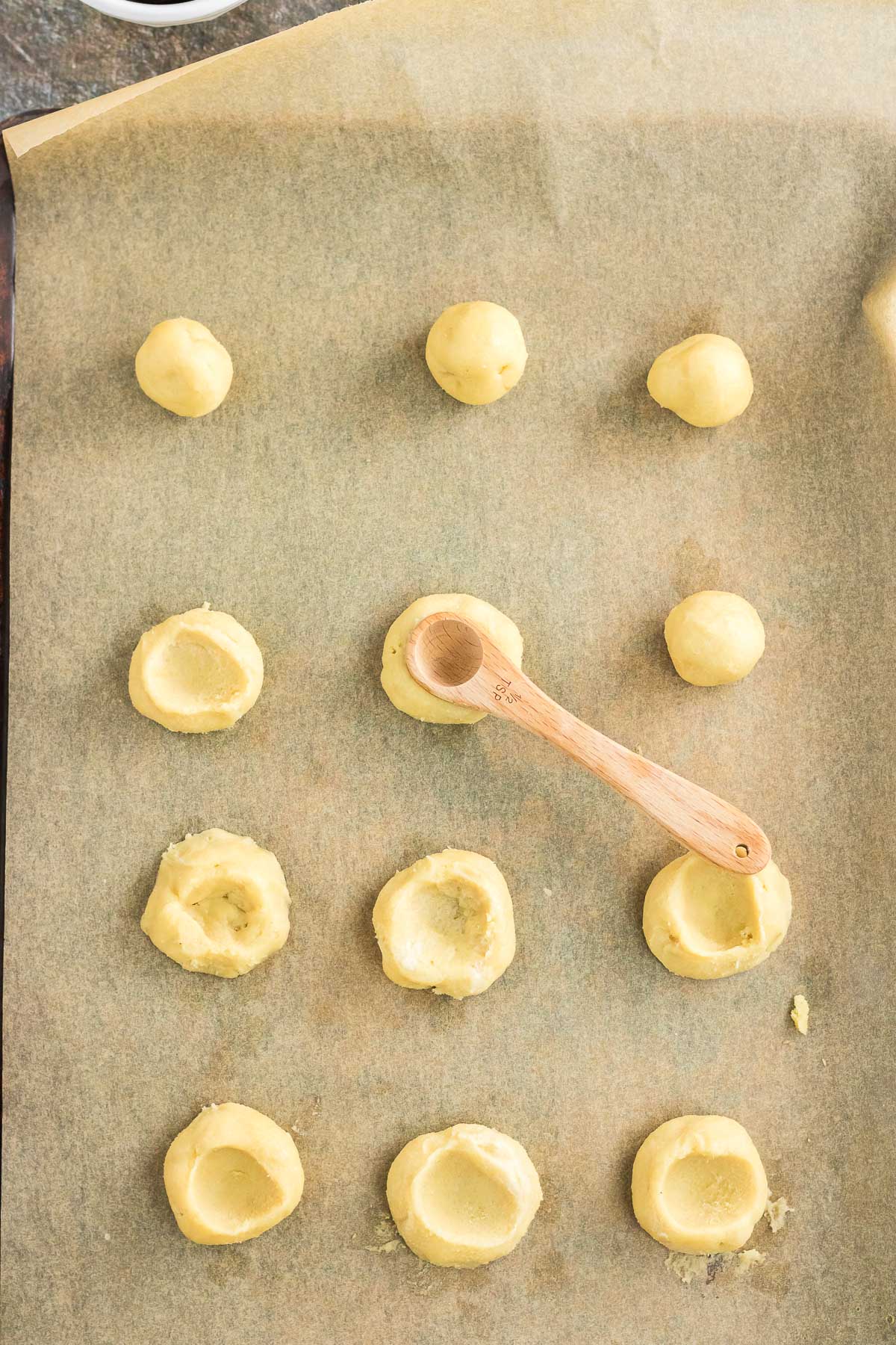 Cookie dough balls rolled out and indented with a spoon.