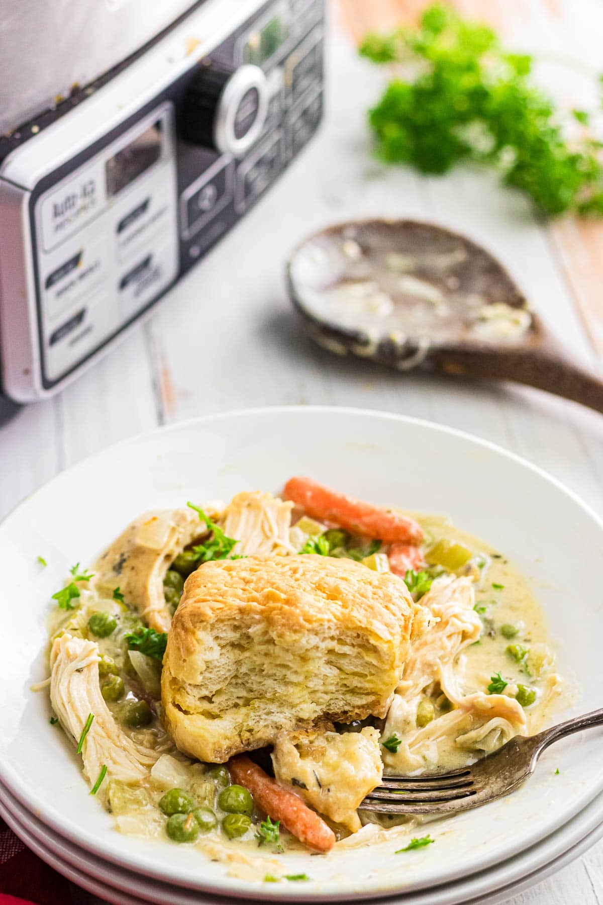 A close-up view of slow cooker chicken pot pie on a plate with a bite taken out of the biscuit.