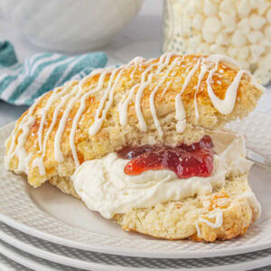 An apricot white chocolate scone split in half and filled with devonshire cream and strawberry jam.