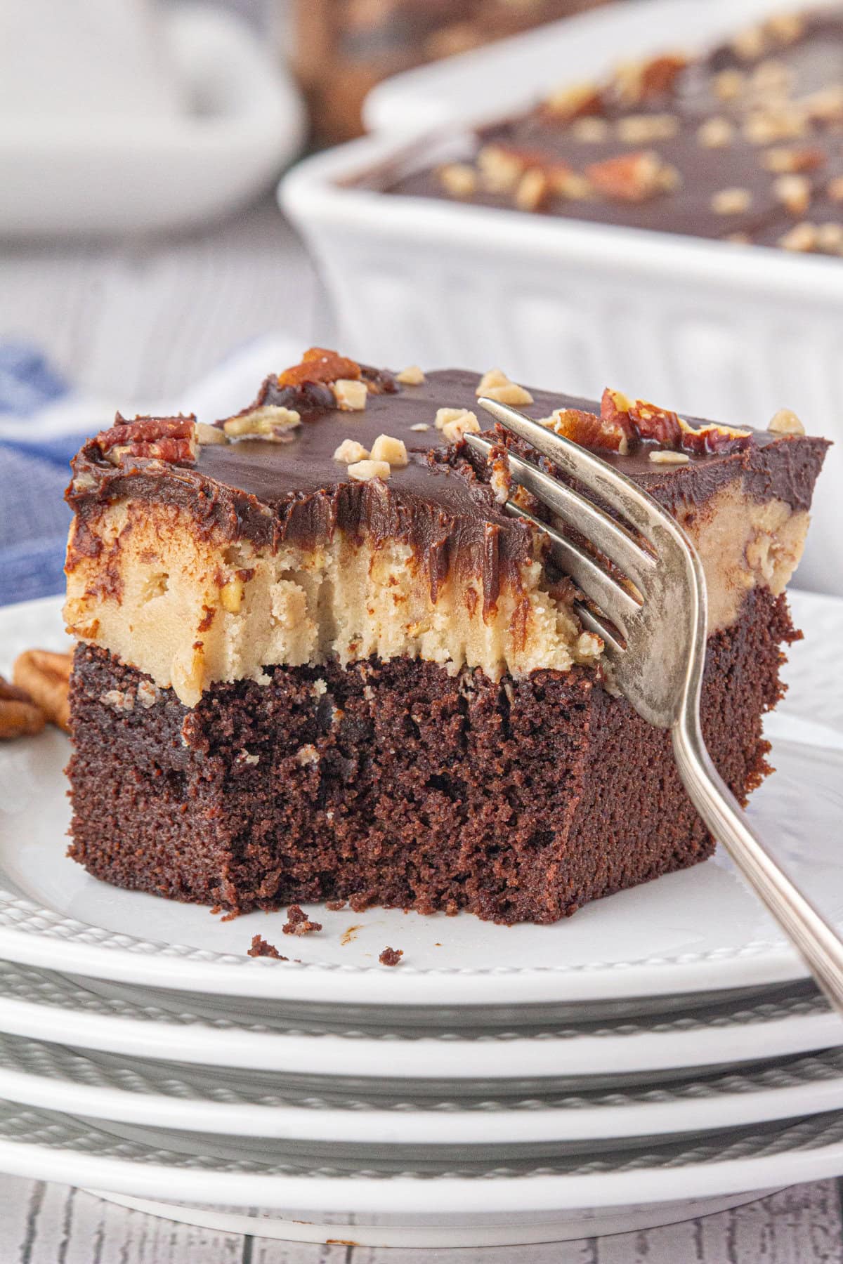 A brownie with a layer of cookie dough and a layer of ganache with a fork cutting into it.