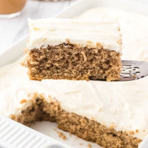 A closeup of a slice of spice cake with maple cream cheese frosting being removed from the pan.