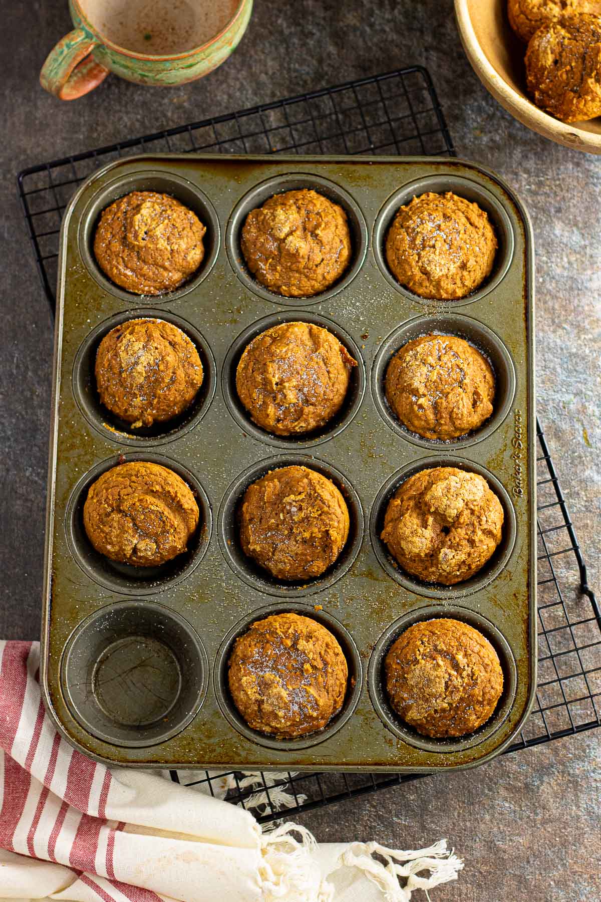 Pumpkin muffins in the muffin tin on a cooling rack.