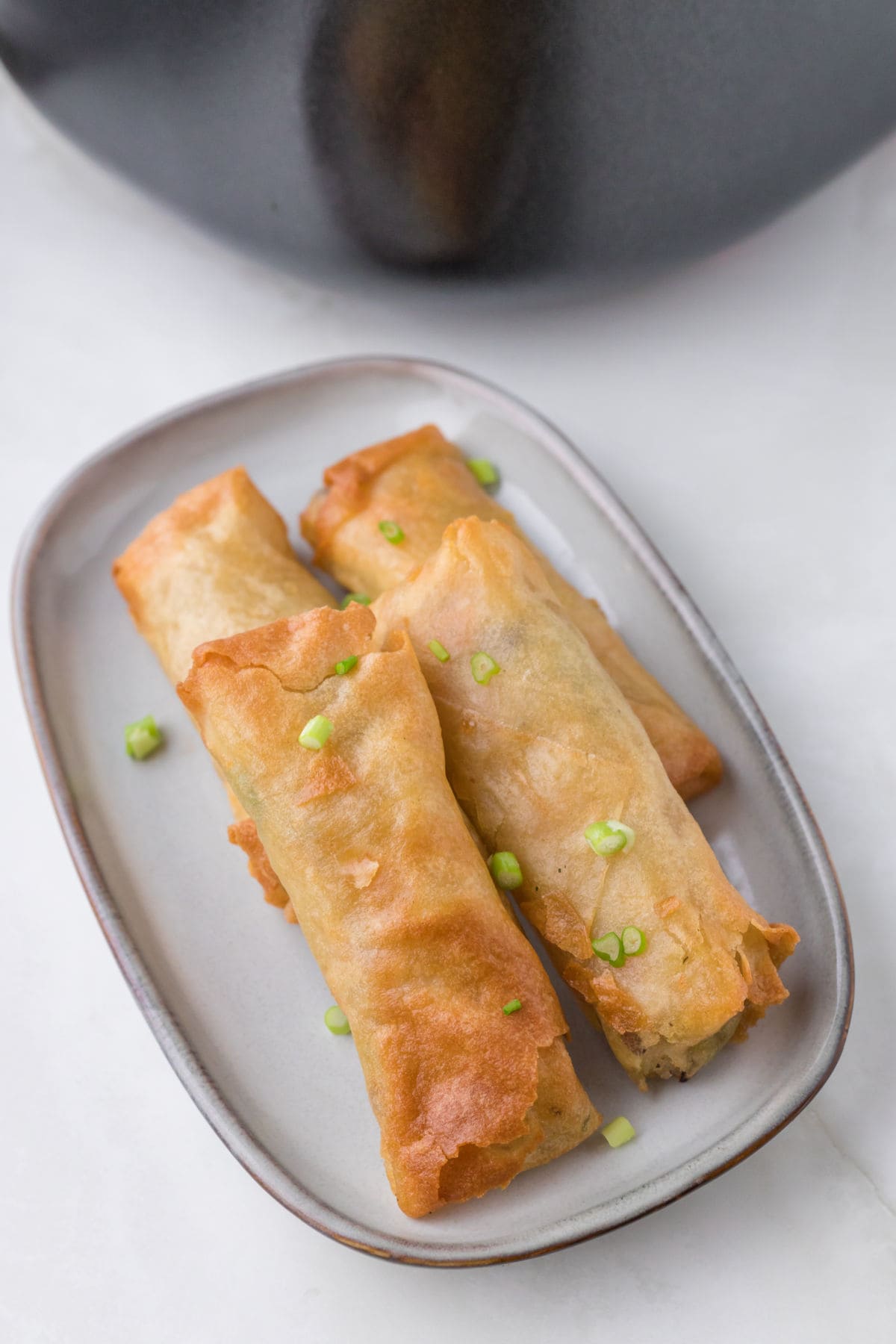 Golden brown spring rolls on a white plate.