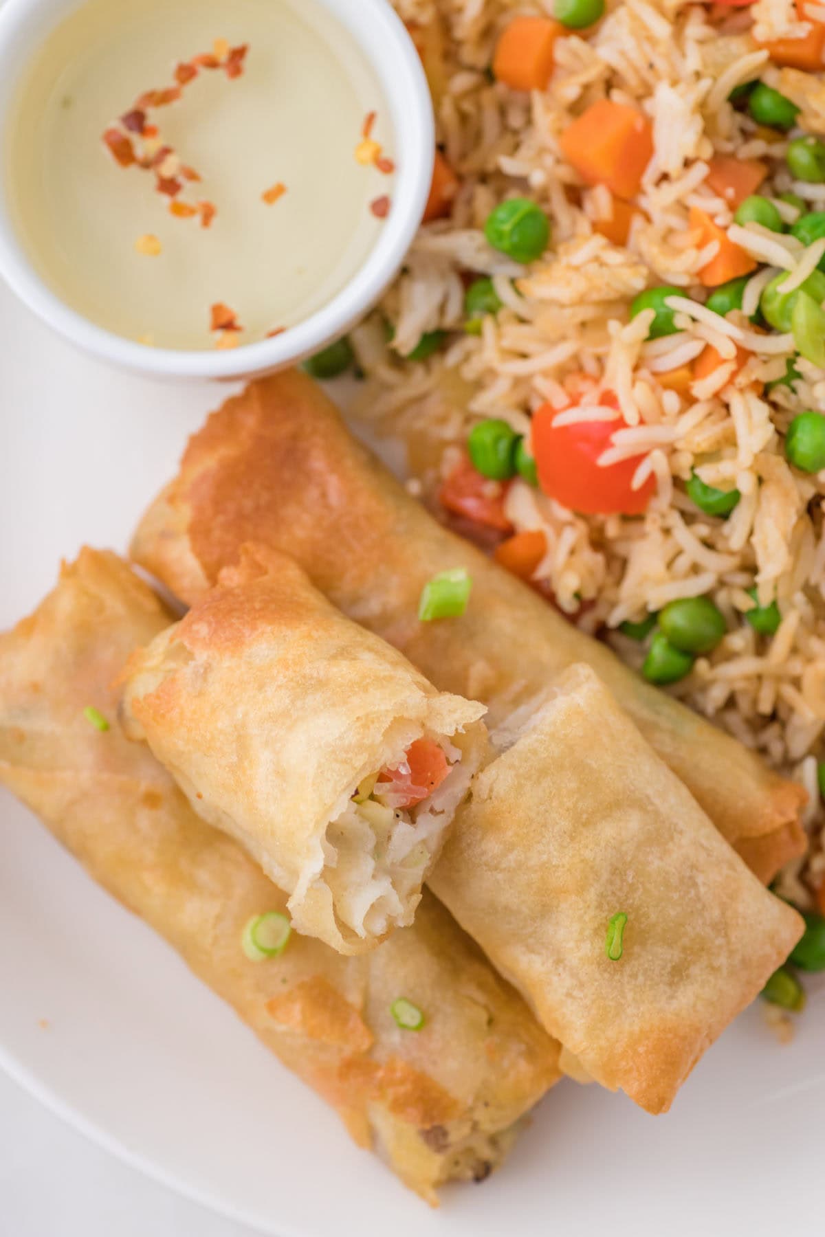 Crispy spring rolls broken open showing the flaky layers and steaming filling.