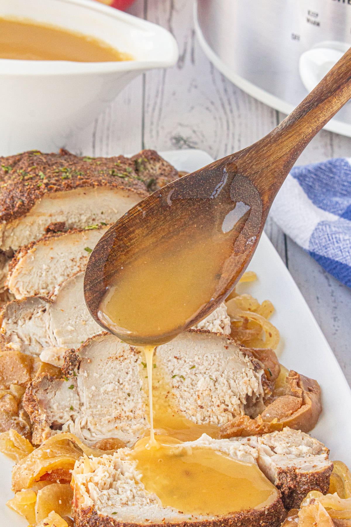 Spooning the apple cider sauce over the slices of pork.