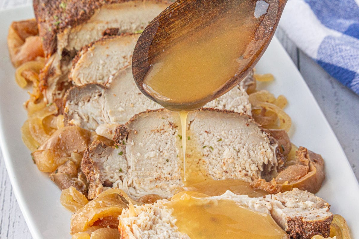 Sauce being drizzled over apple cider pork roast.