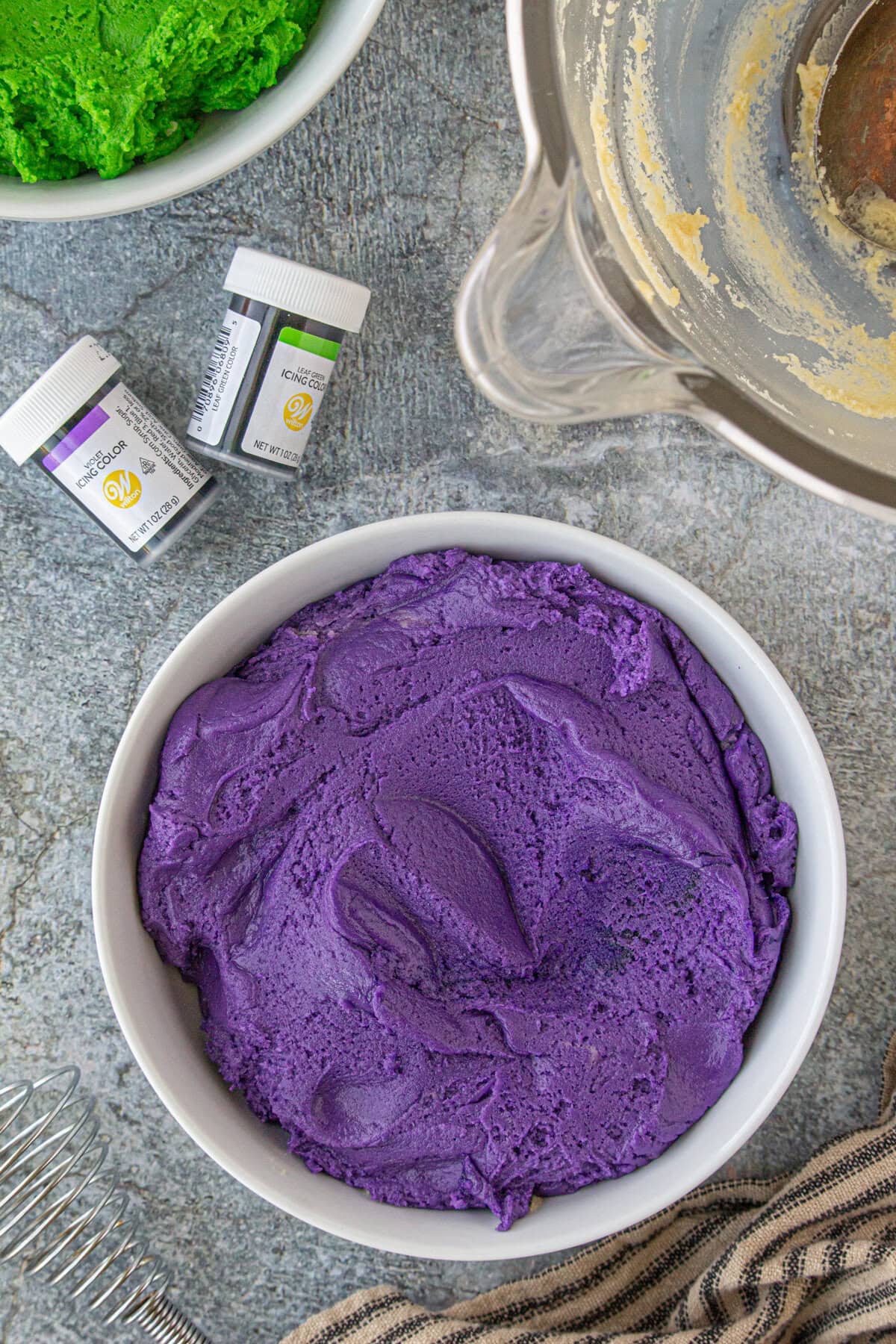 Purple dyed dough in a bowl with green dyed dough in another bowl.