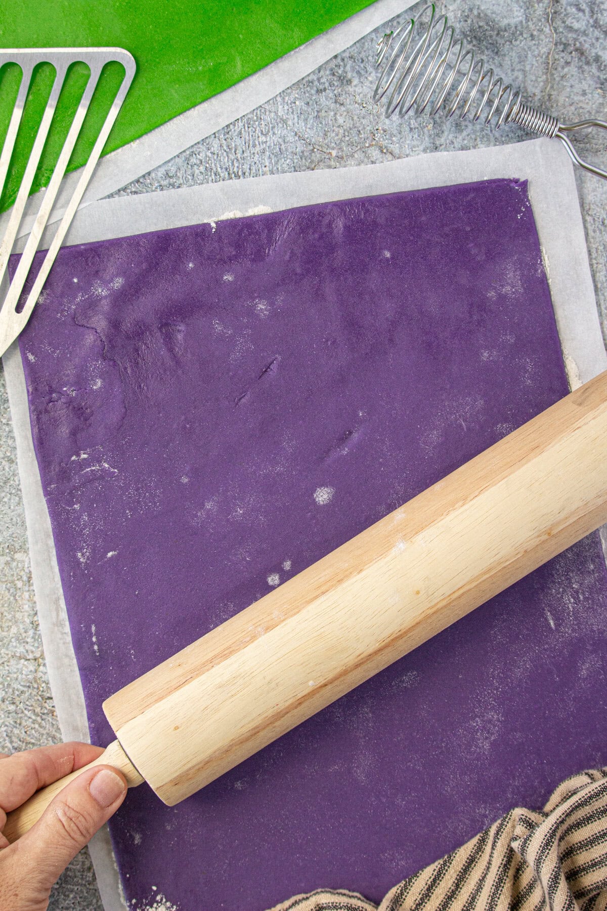 A rolling pin rolling out the purple dough.