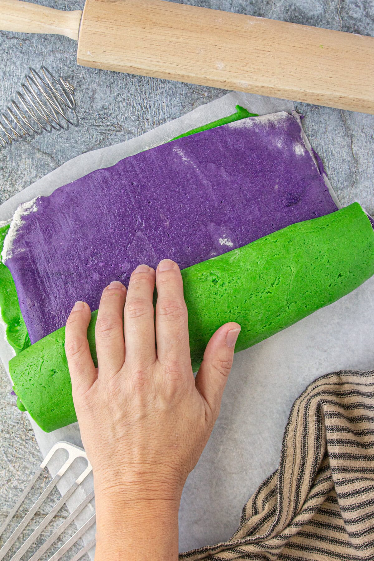 Rolling the purple and green dough together the make the swirl.