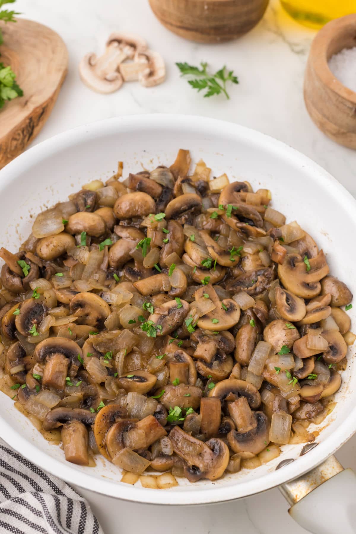 Overhead view of a pan of caramelized onions and mushrooms with bright green parsley sprinkled on top.