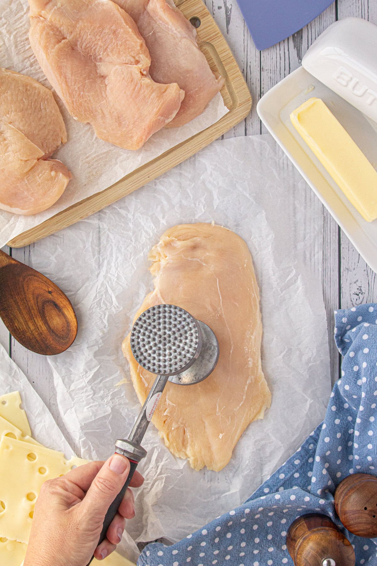 Pounding the chicken thin with a meat mallet.