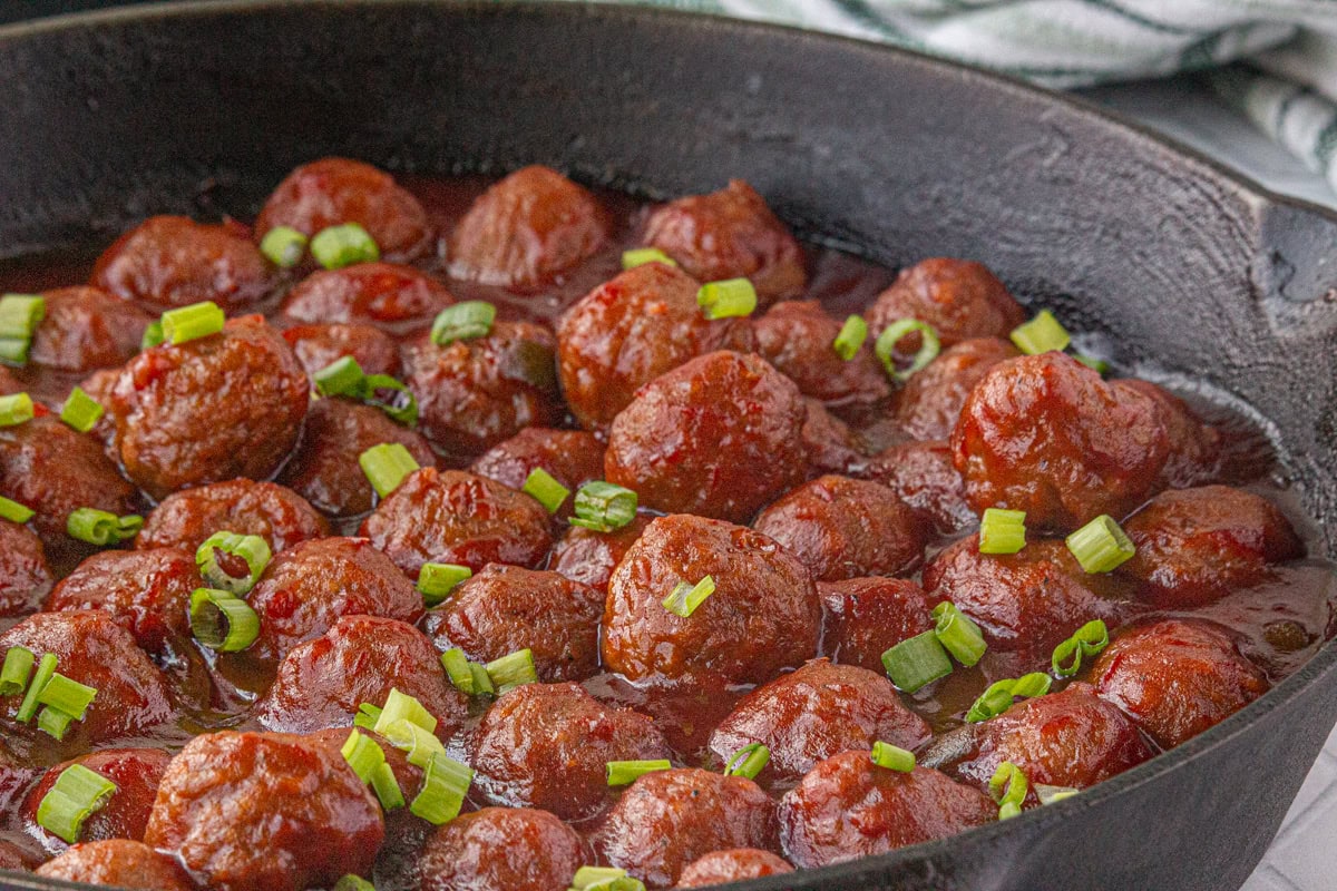 Cranberry meatballs in an iron skillet.