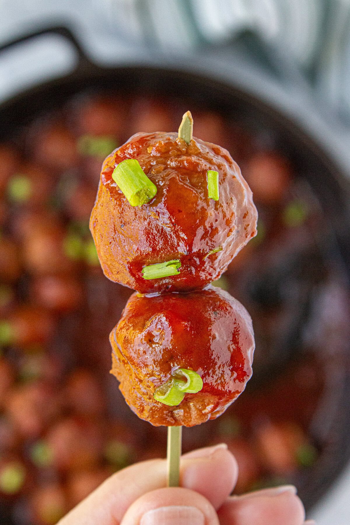 Two cranberry sauce meatballs on a toothpick.