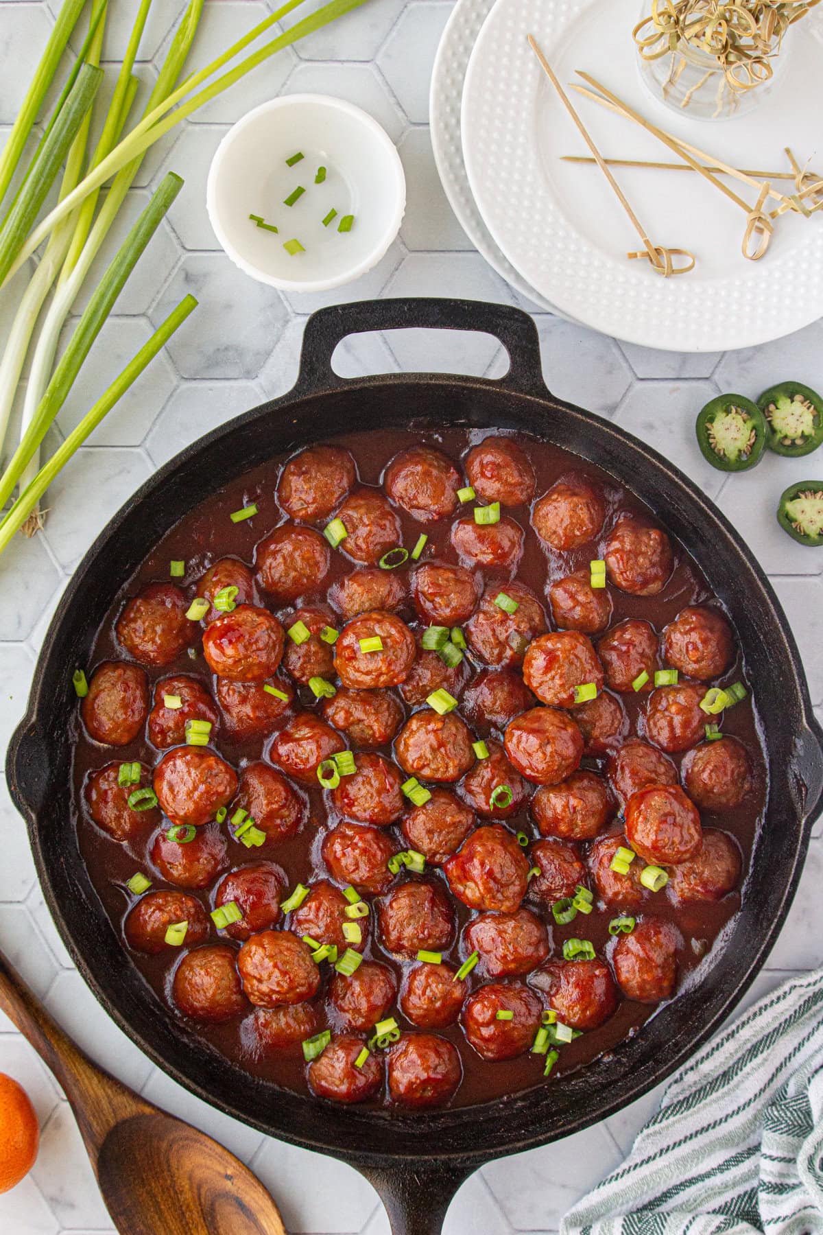 The cooked meatballs in cranberry sauce topped with green onion.