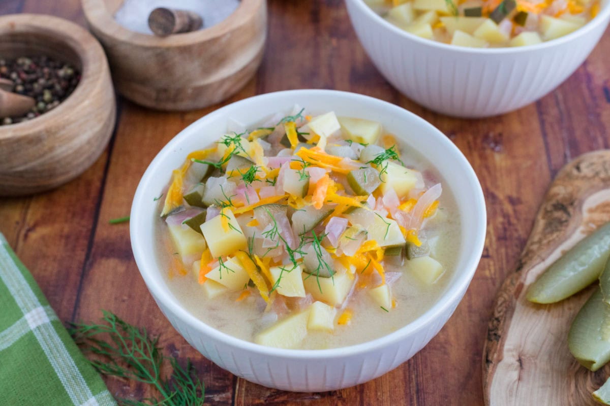 A bowl of dill pickle soup on a table.