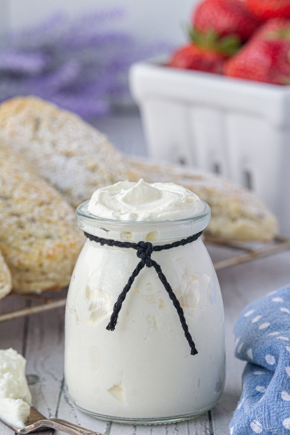 Mock clotted cream in a jar with scones in the background.