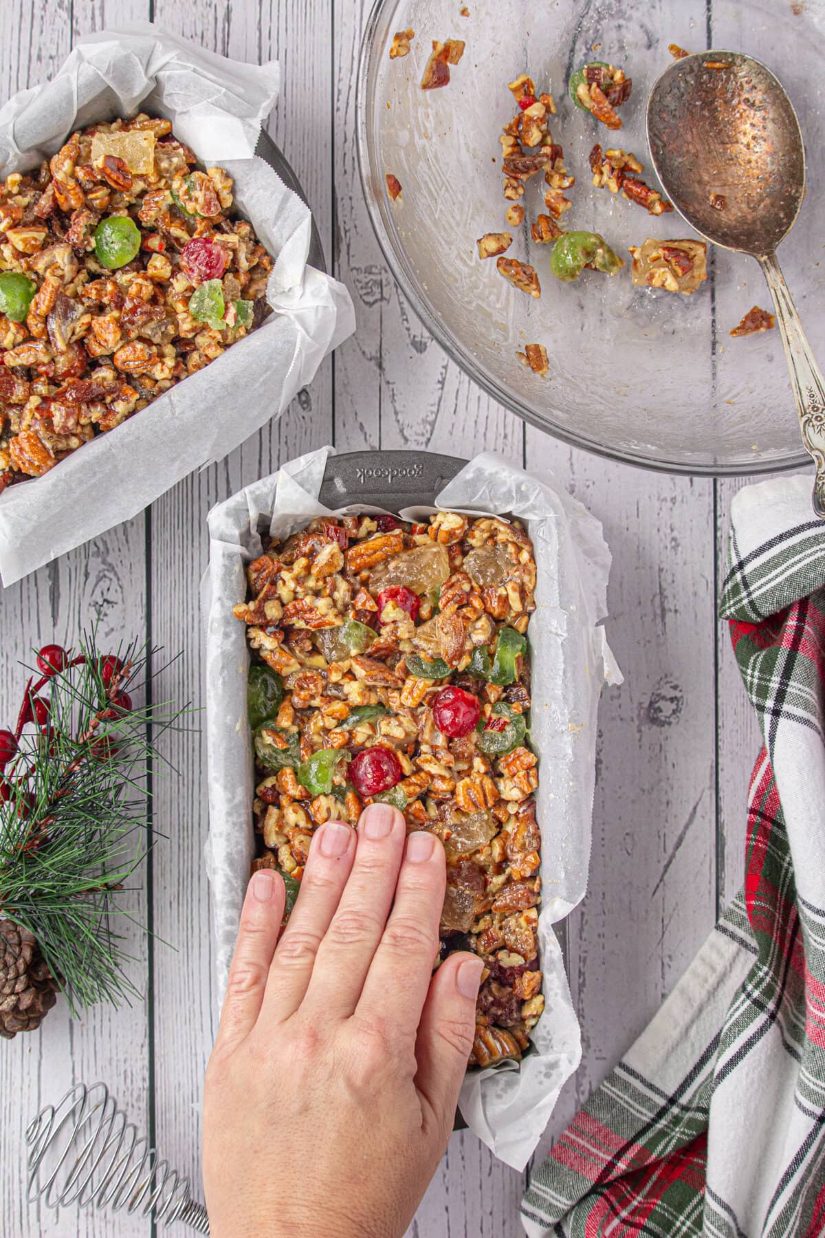 Fruitcake mixture being pressed down into loaf pans ready to be baked.