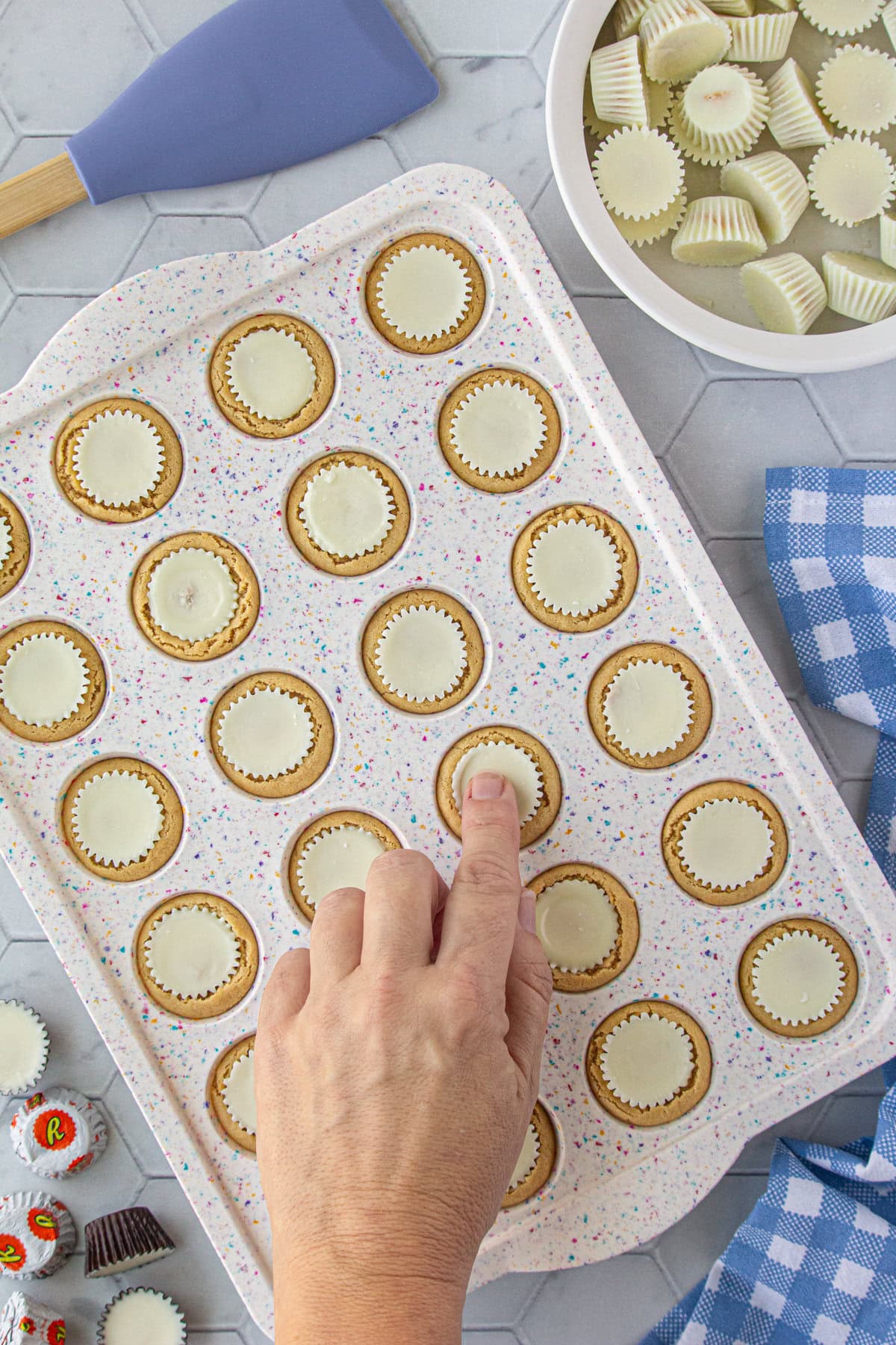 Pressing the white chocolate peanut butter cups into each baked cookie.