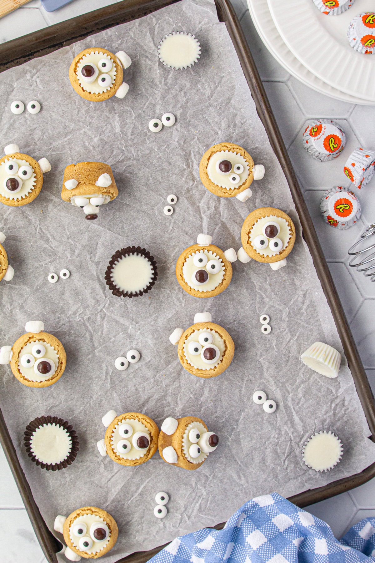 Christmas polar bear cookies and white chocolate peanut butter cups scattered on a baking sheet.