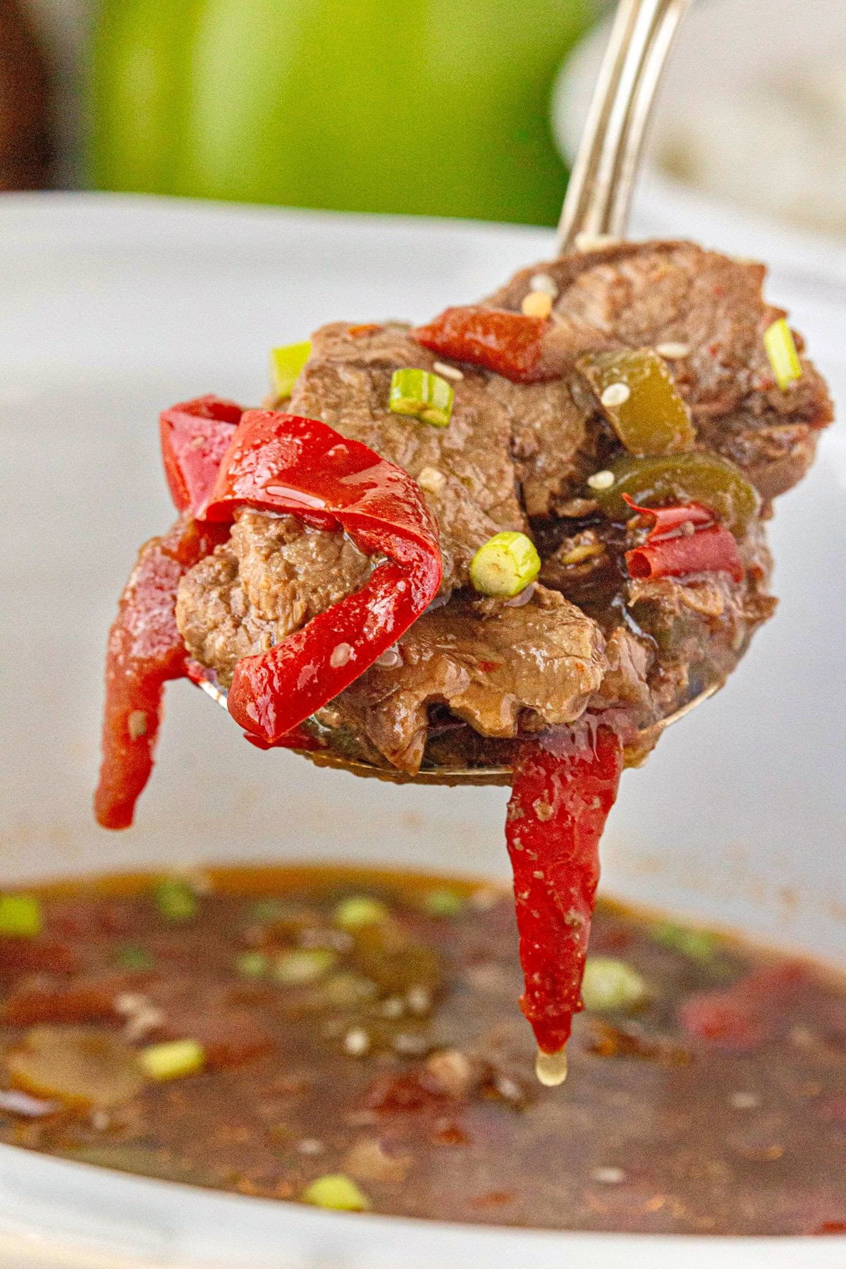 A close-up photo showing the texture of the slow cooker pepper steak on a serving spoon.