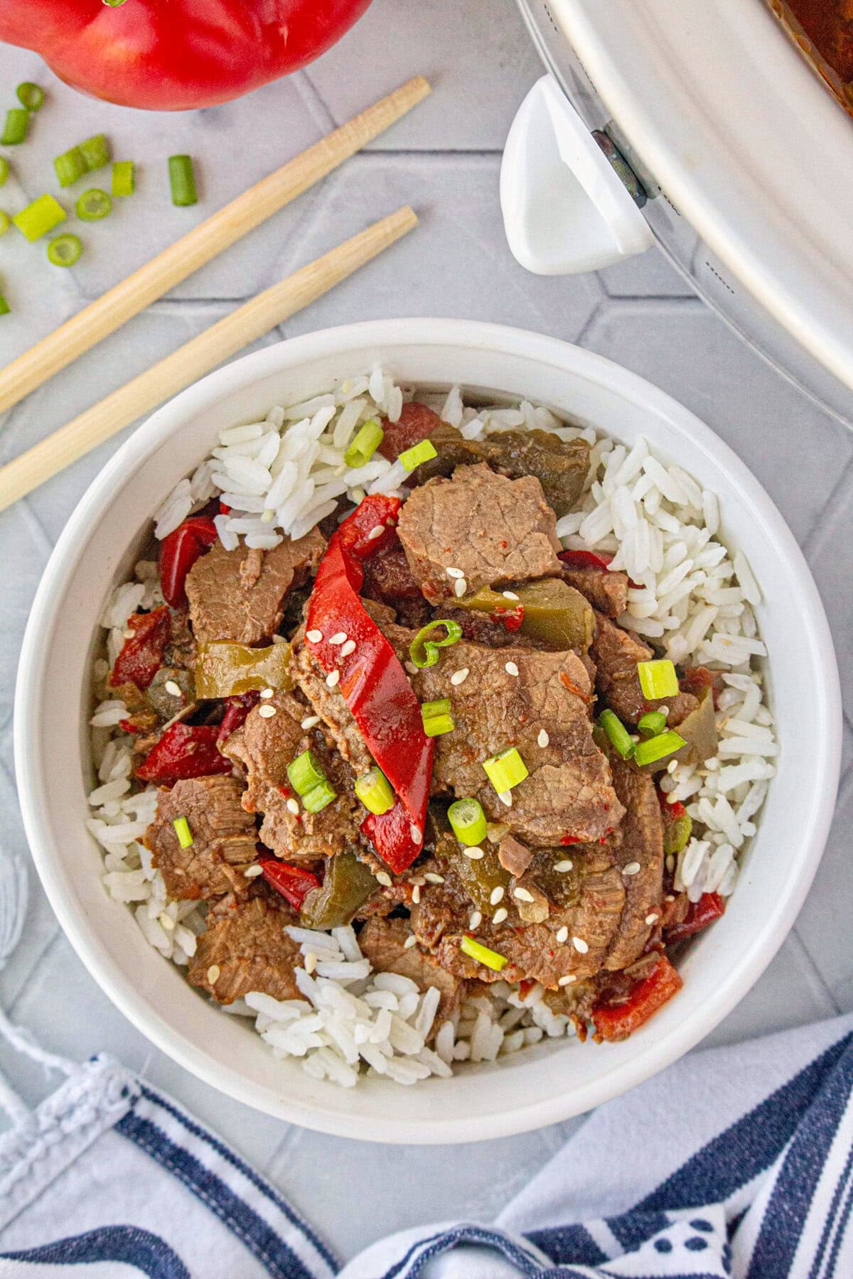 An overhead view of slow cooker pepper steak over rice in a bowl.