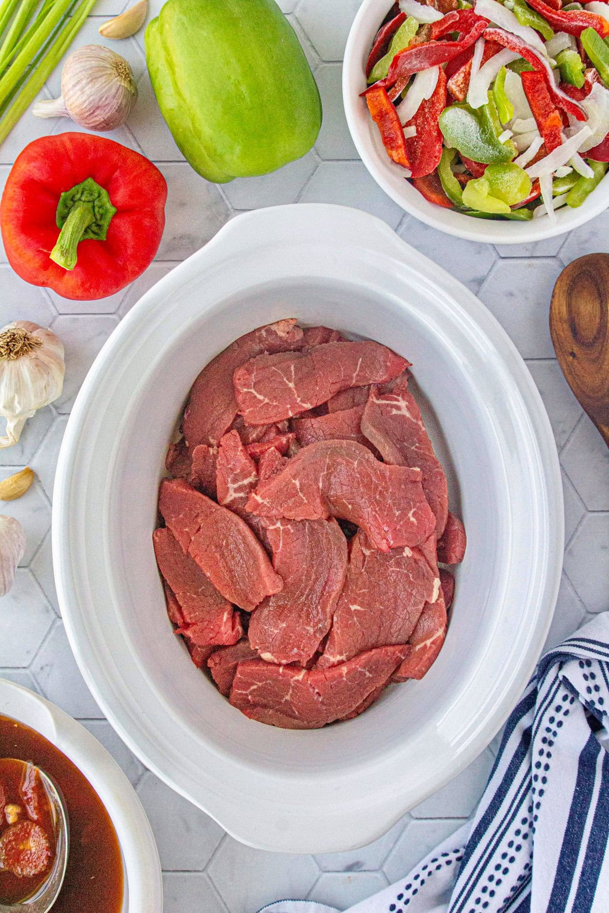 The beef strips in the bottom of the slow cooker.