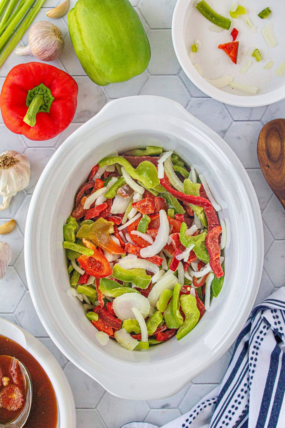 The frozen peppers and onions added to the beef in the slow cooker.