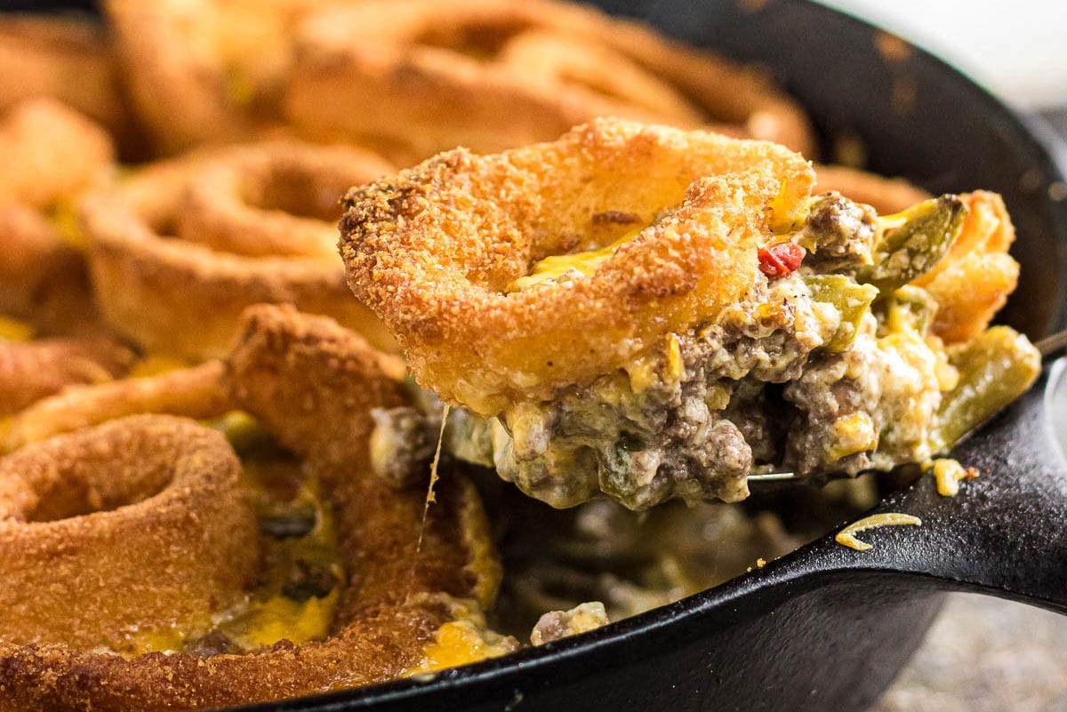 Beef and green bean casserole being served from a cast iron skillet.