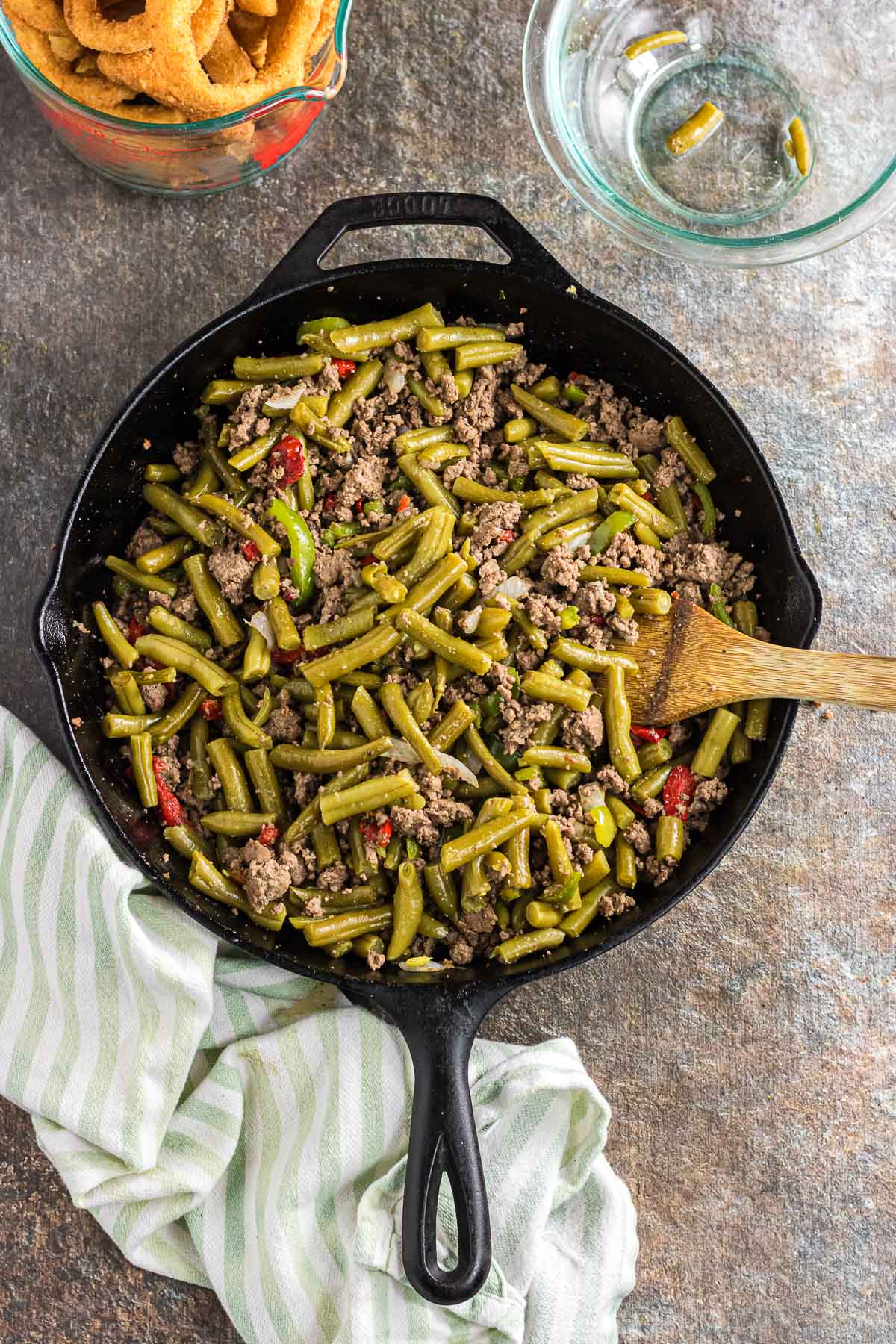 Stirring the green beans into the ground beef mixture in the skillet.