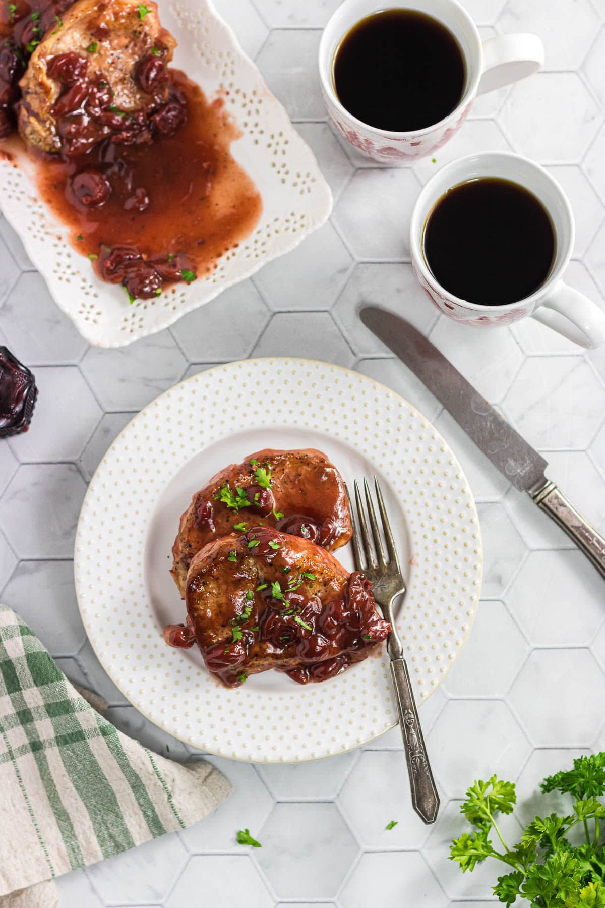 Two slow cooker cherry chipotle pork chops on a dinner plate.