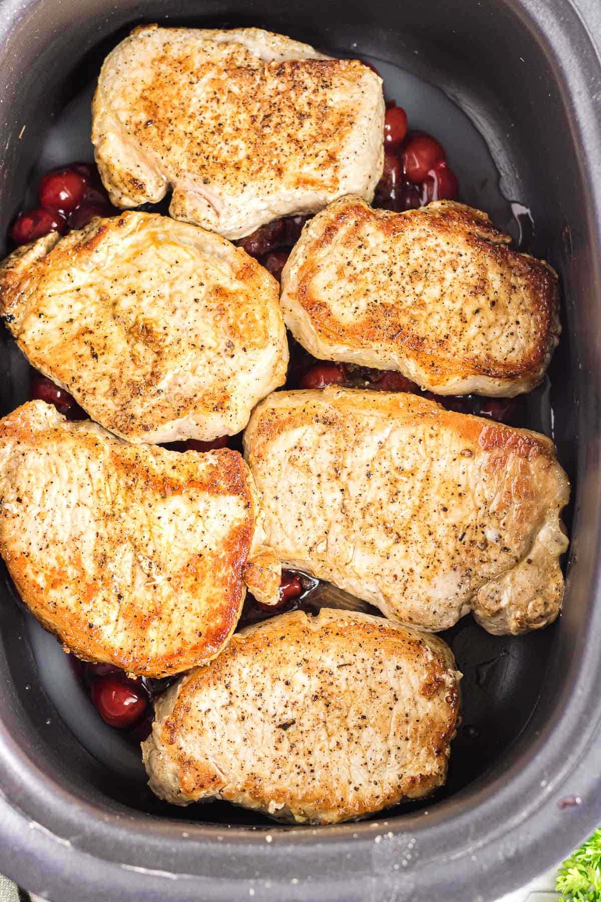 Seared pork chops laid on top of the cherry pie mixture.