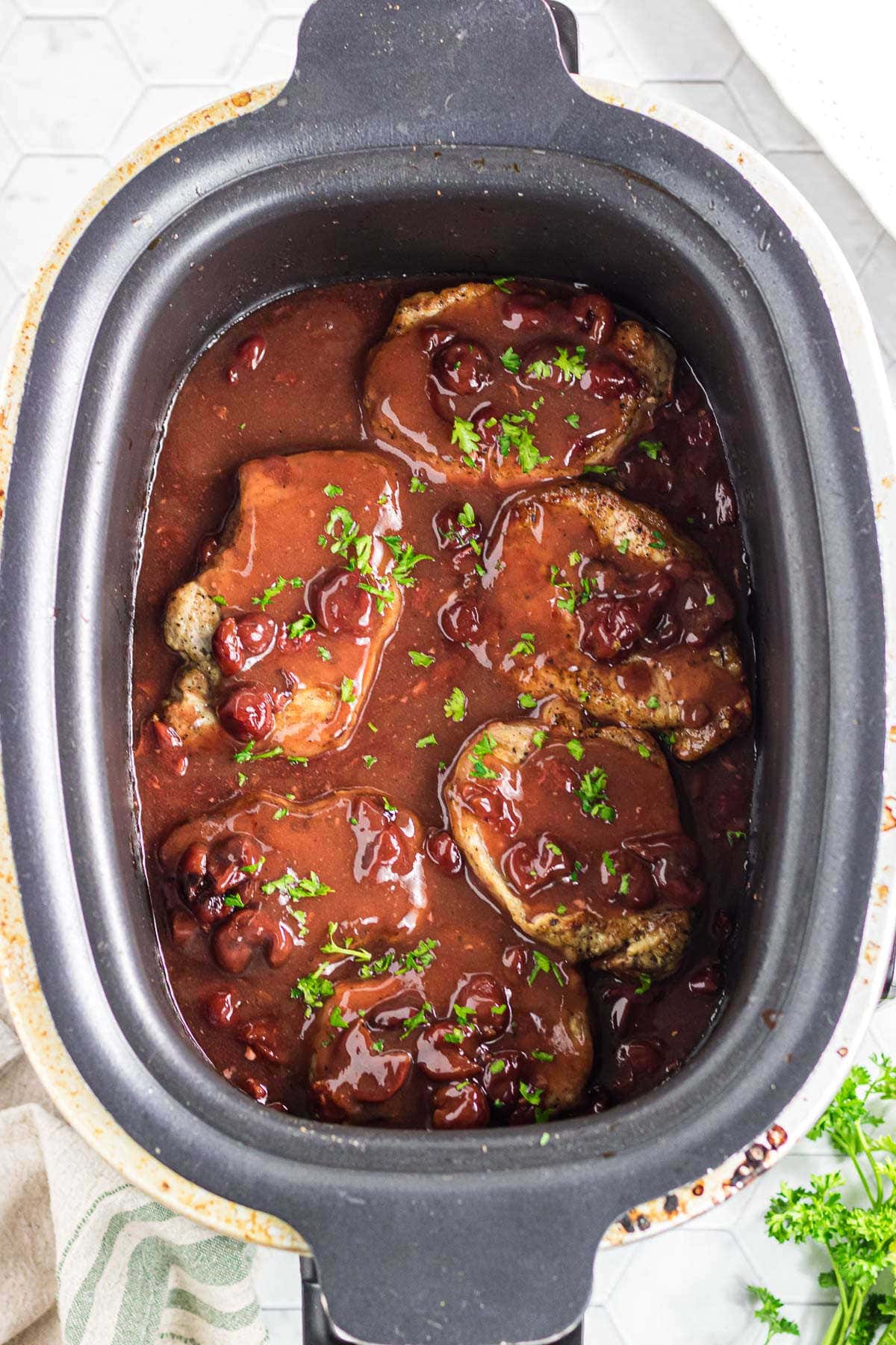 The cherry chipotle pork chops in the slow cooker with parsley on top.