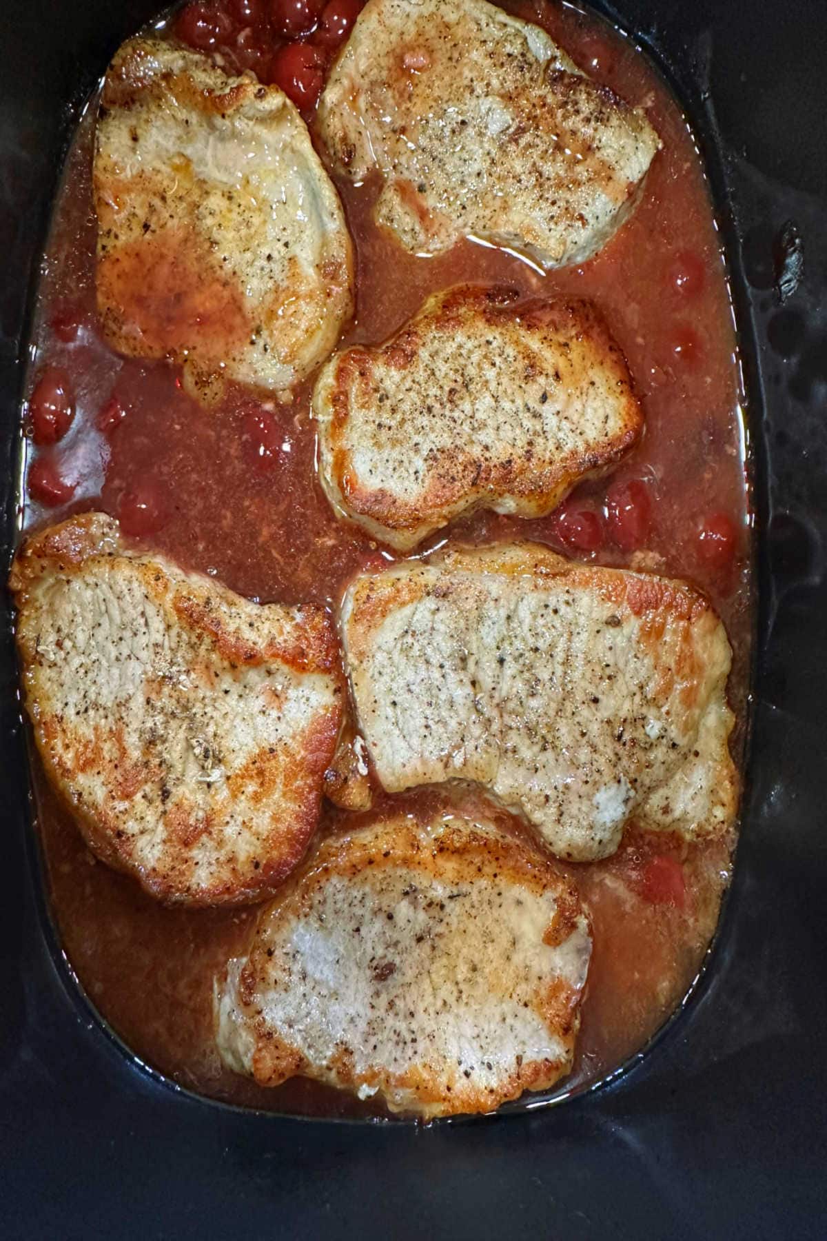 The pork chops cooking in the slow cooker.